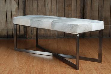 Grey leather bench with zinc metal base in a rustic setting