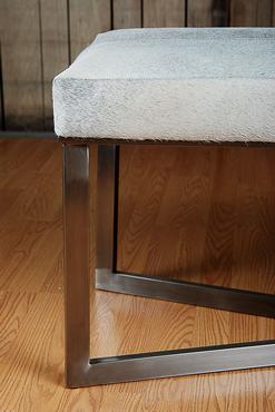 Grey leather bench with a zinc frame and a wooden floor in the background.