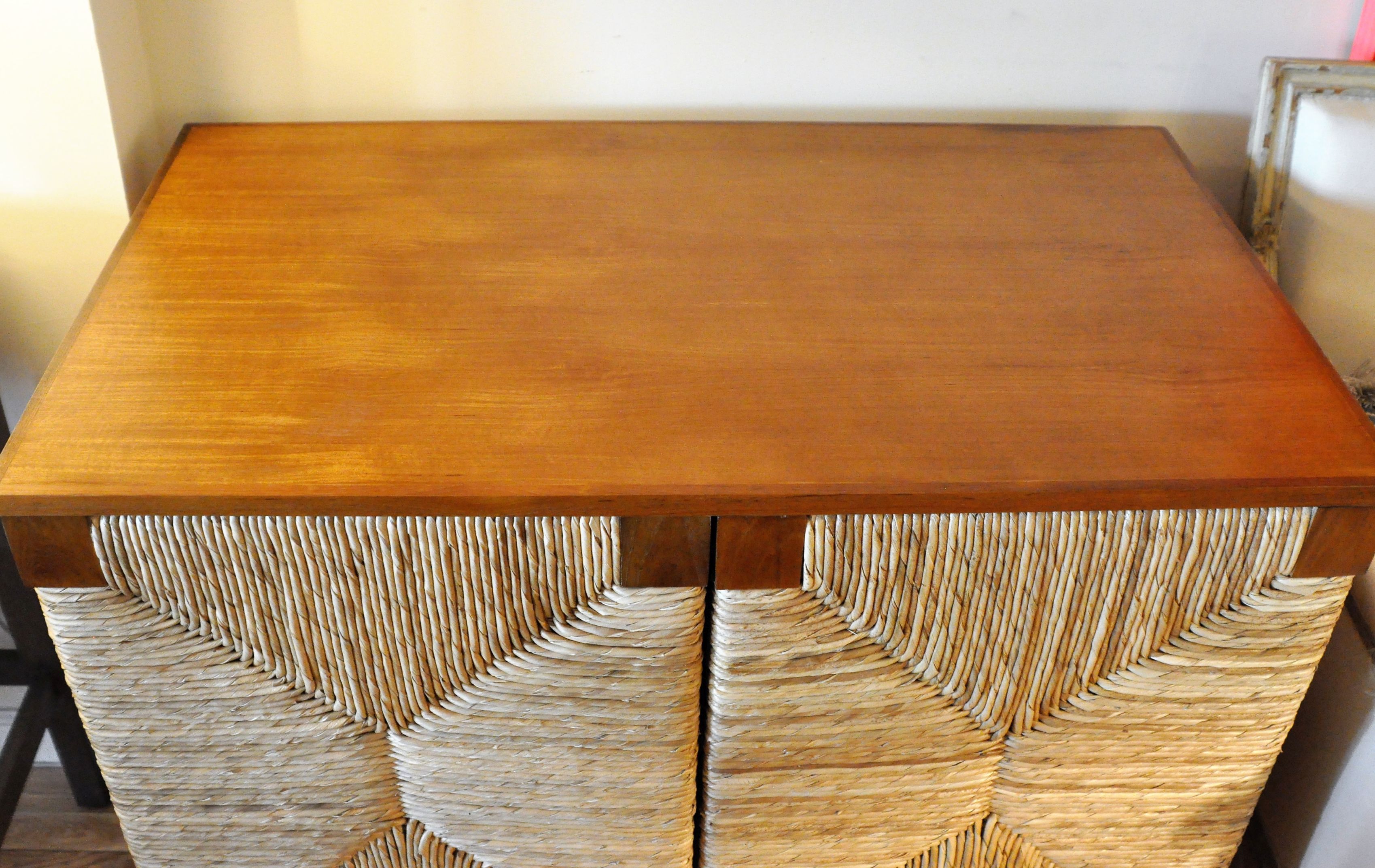 A wooden buffet with a woven texture on its doors and sides, displayed in a room against a wall.