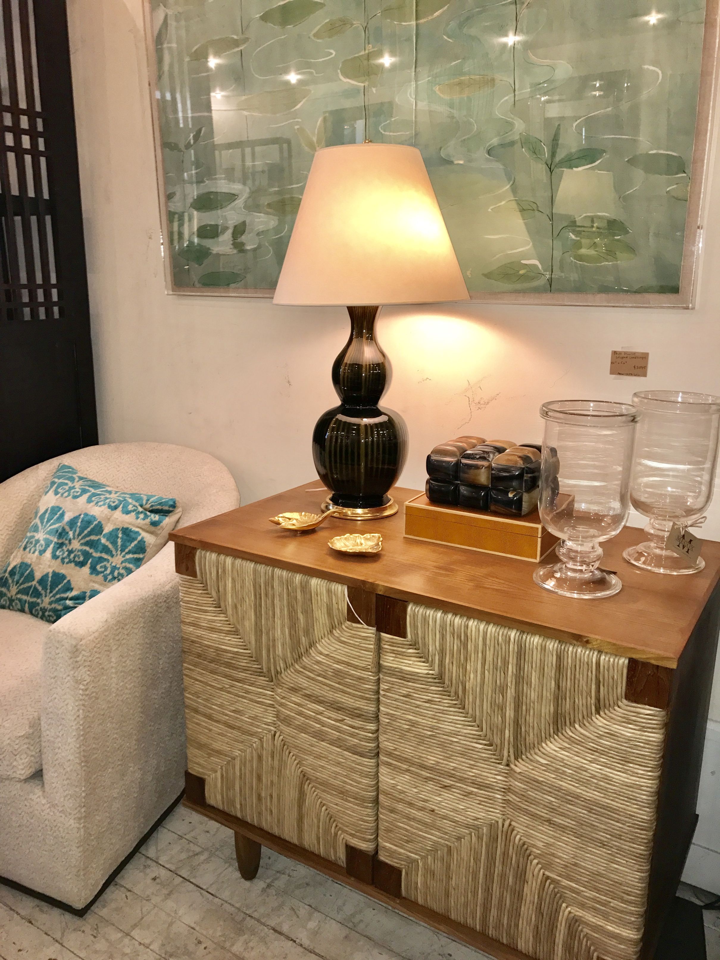 Small wooden buffet with two doors and a lamp on top placed in a room with a blue pillow on a chair
