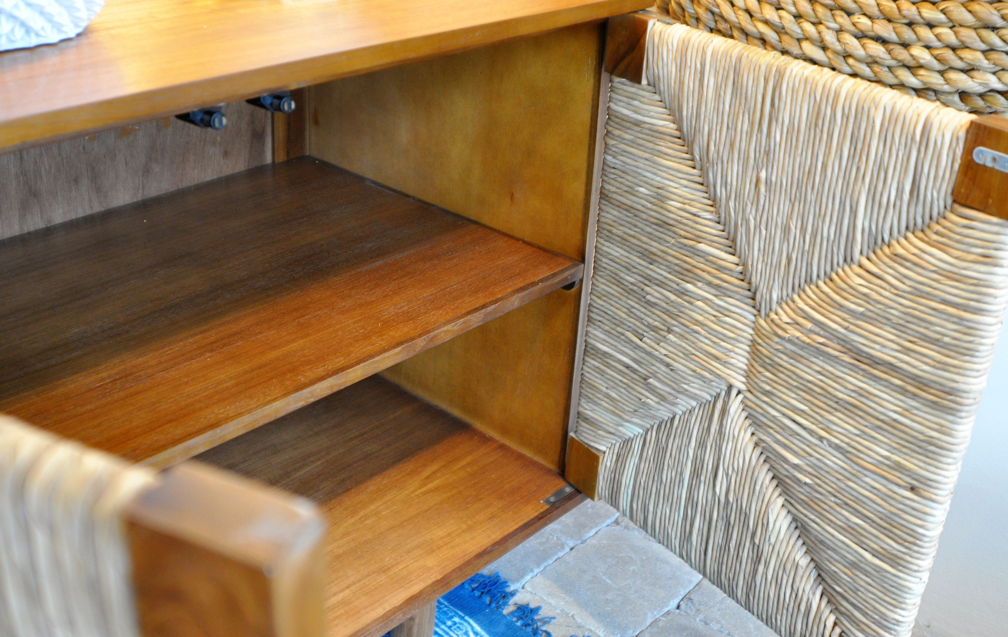 This image shows a small buffet with two doors, featuring a woven design on the front panel and a wooden finish.