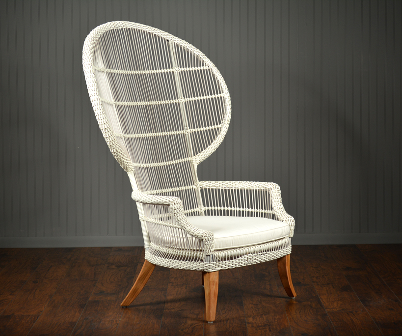 The image shows a wicker chair with a teak frame and a cushioned seat, placed against a wall.