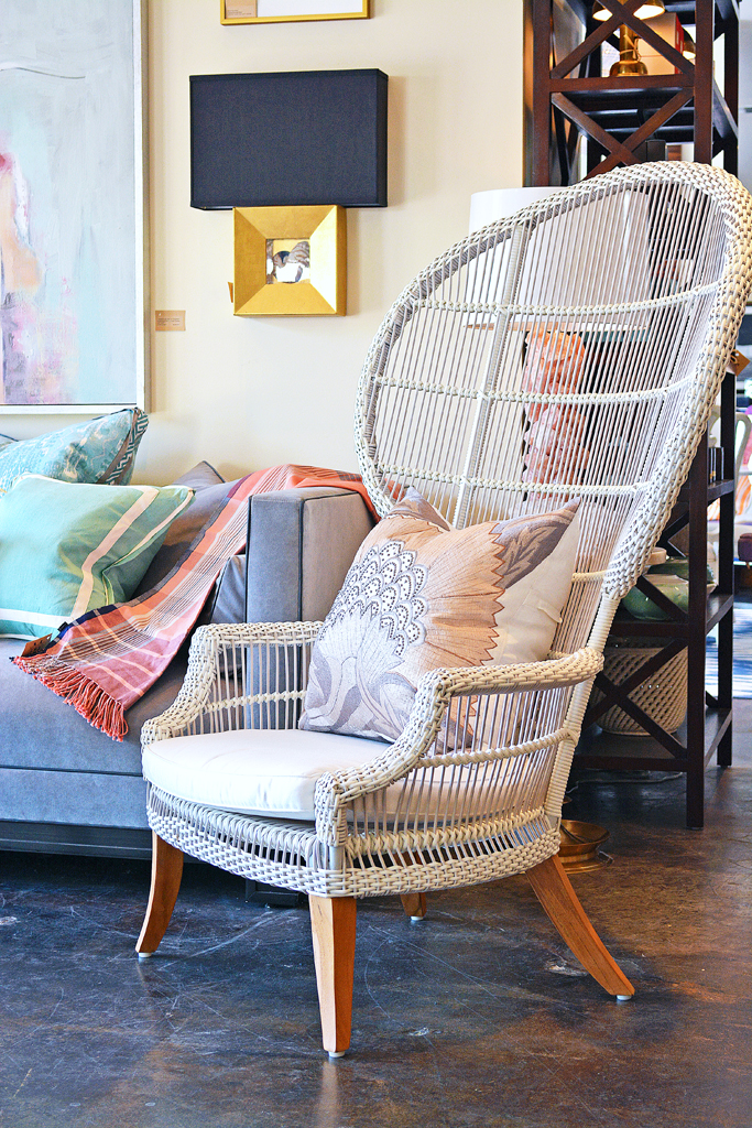 An Elizabethan outdoor chair with teak legs and a sunbrella seat pillow available in brown rattan aged natural rattan and white rattan