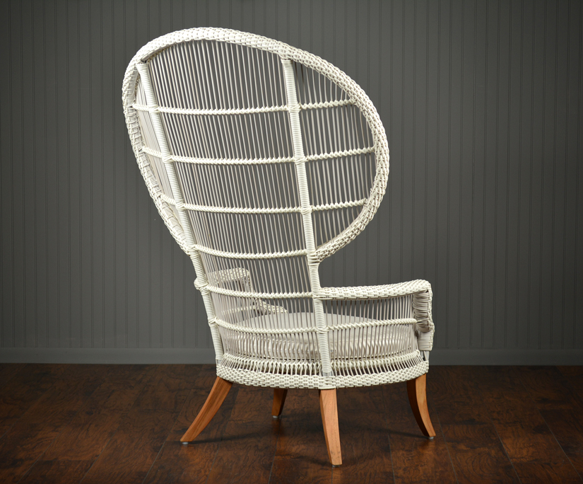 An Elizabethan outdoor chair with a wicker seat and teak legs, set against a dark background.