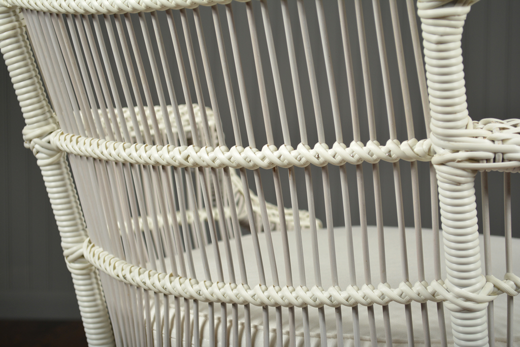 Wicker outdoor chair with a cushioned seat, featuring a woven design and teak legs.