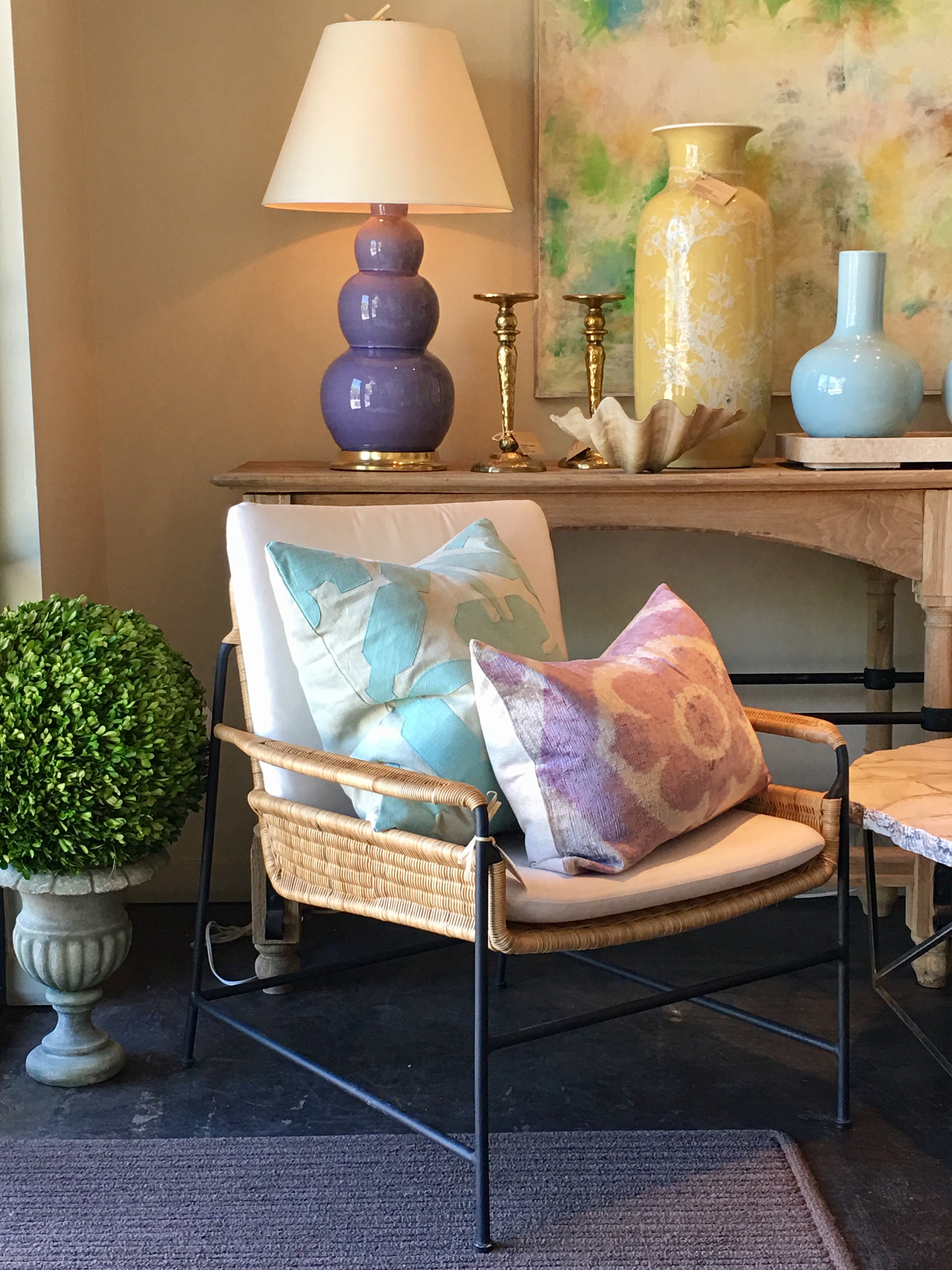 Antibes woven rattan and iron club chair with canvas natural sunbrella fabric seat and back cushion in a room with a lamp