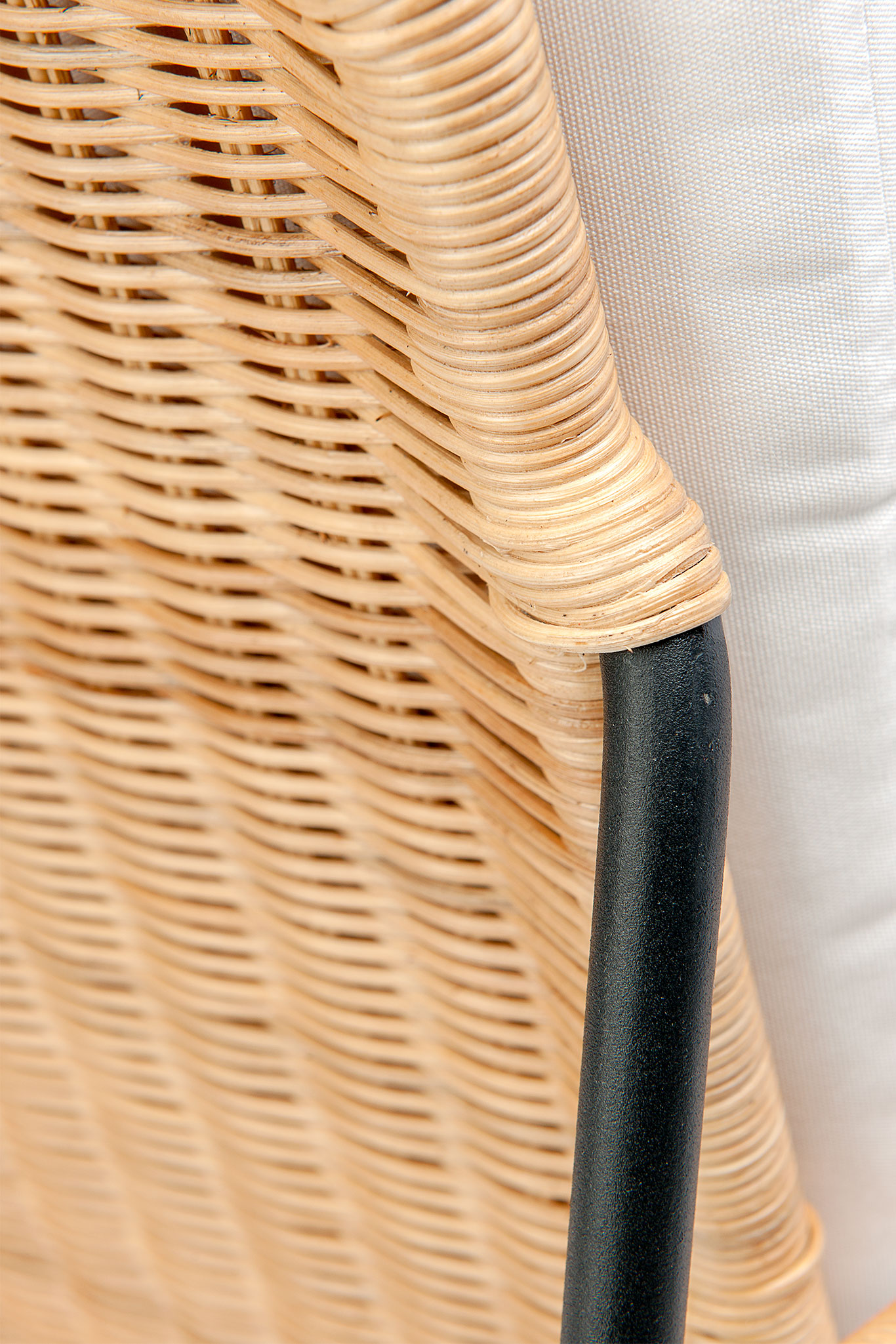 The image displays a wicker chair with a cushioned seat and backrest, showcasing its design and texture.