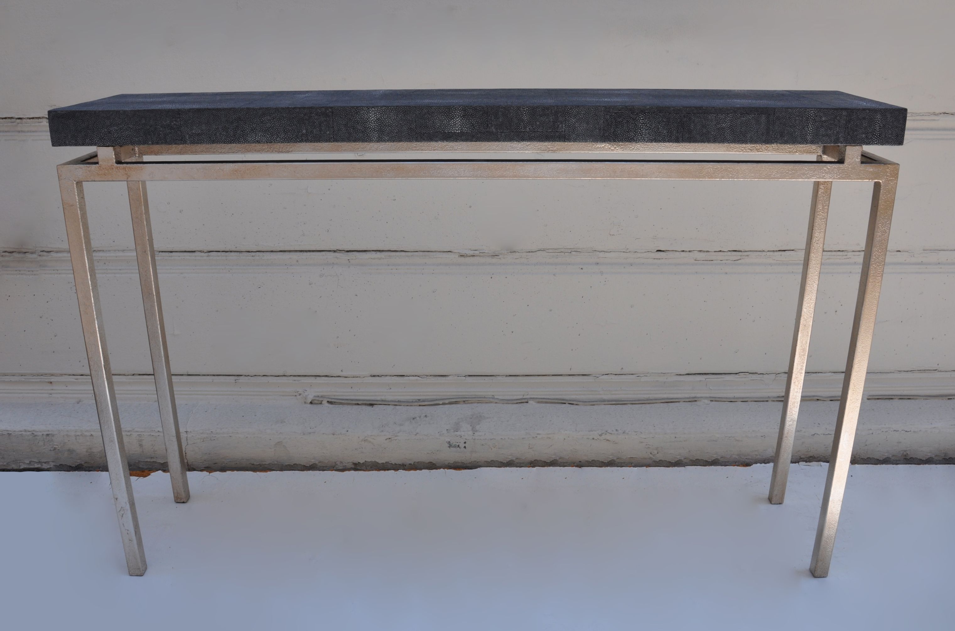 Small black console with a rectangular top and two side shelves, featuring a modern design with clean lines and a sleek appearance.