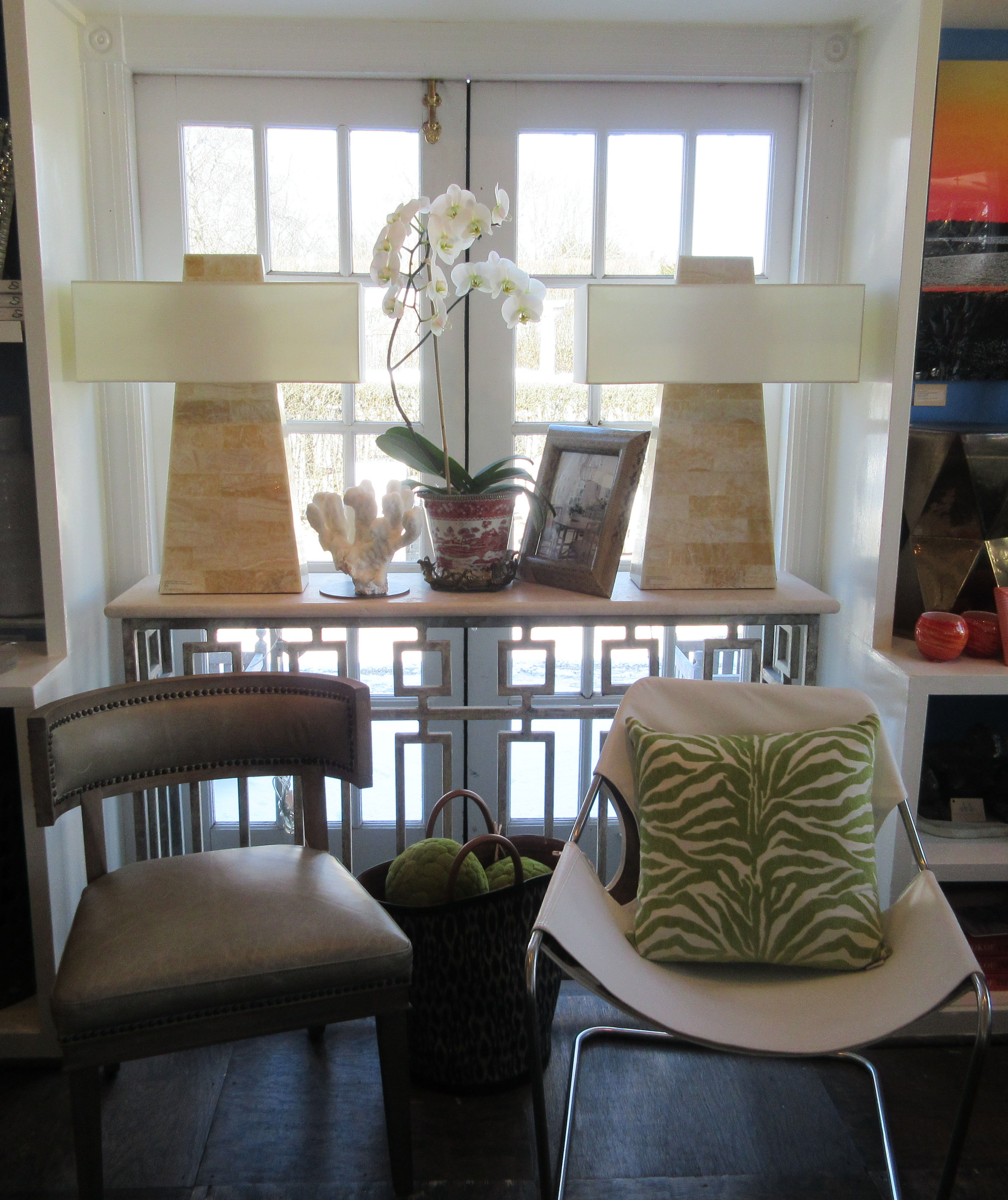 A console table with a light travertine top and metal frame in a deep ocean finish placed against a wall with a