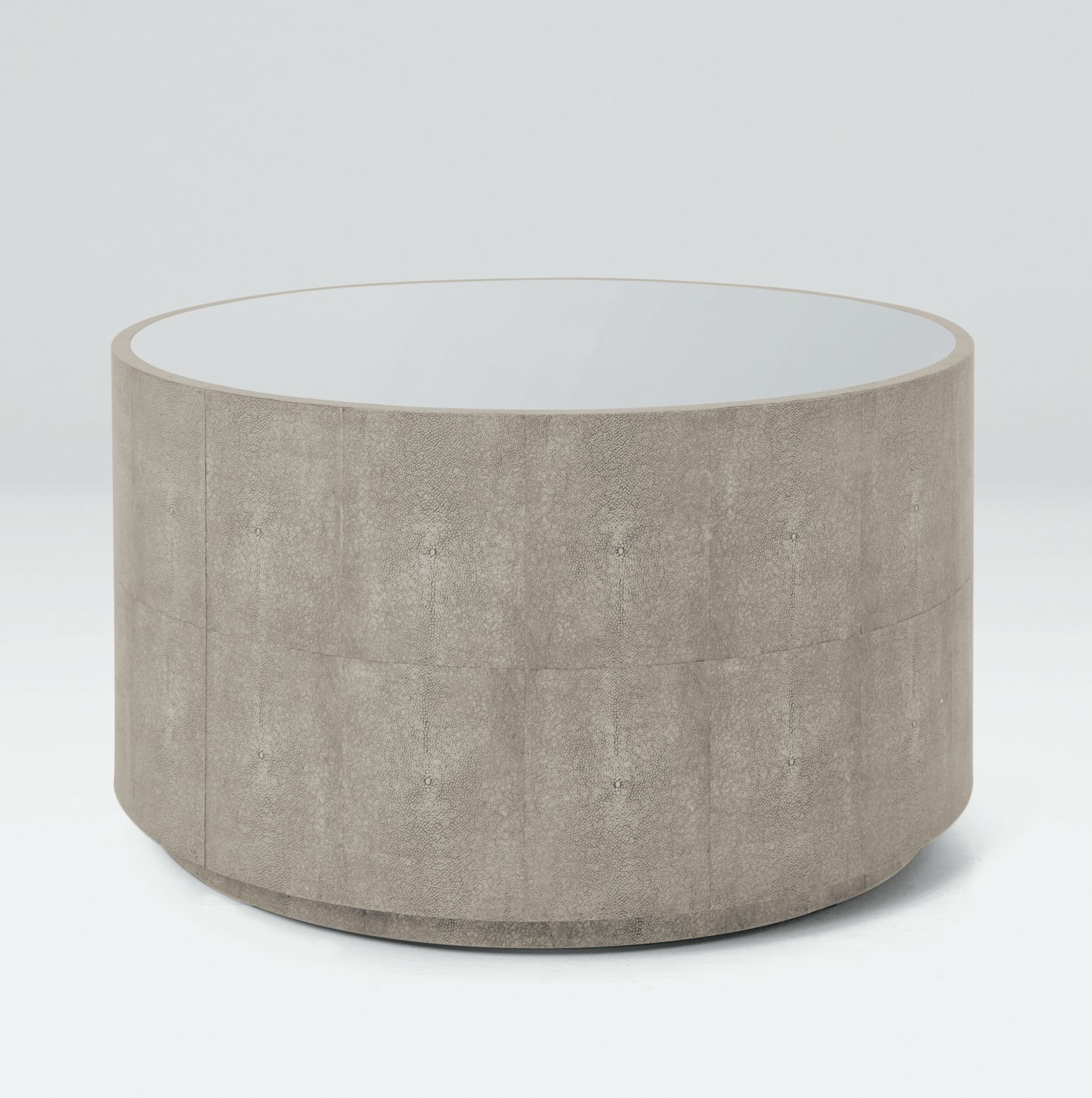 A round, modern coffee table with a faux shagreen finish and an antiqued mirror top.