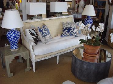 A white and blue patterned sofa in a store accompanied by a blue and white patterned throw pillow and a vase with