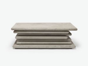 A stacked concrete coffee table with three tiers presented in a light gray aged concrete finish showcasing natural variation in color tones