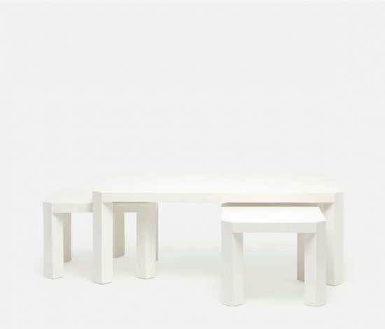 A set of three nesting tables with angled legs presented in a minimalist white background The largest table is positioned centrally while