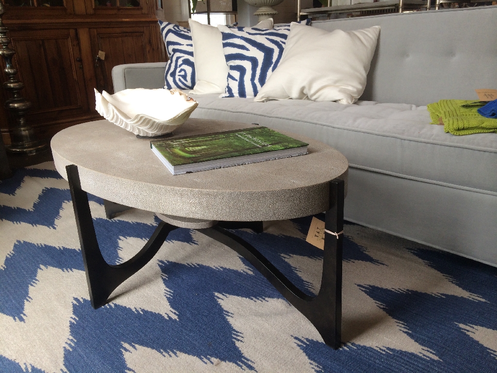 A modern coffee table with a marble top and metal frame placed on a blue and white patterned rug in a living