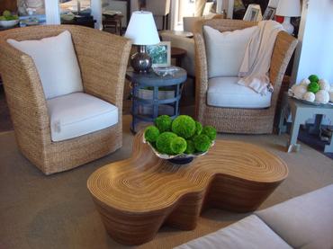 A modern organic striped wood coffee table with a contemporary undulating shape set against a backdrop of a cozy living room with
