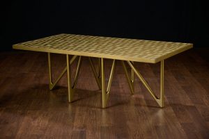 Gold and brass coffee table with geometric pattern on a dark wooden floor.
