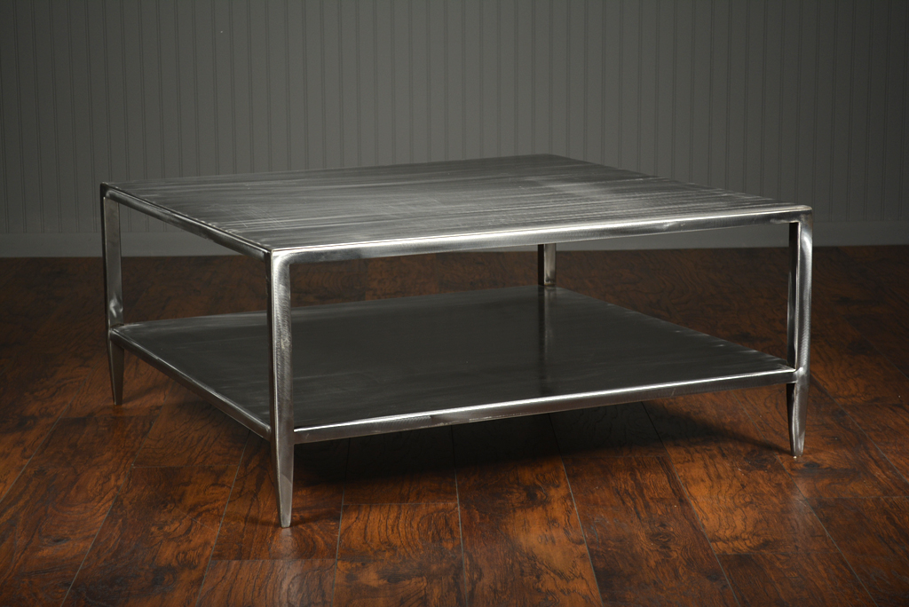 Brushed steel coffee table with two levels and slightly tapered legs, featuring an open bottom shelf on a wooden floor.