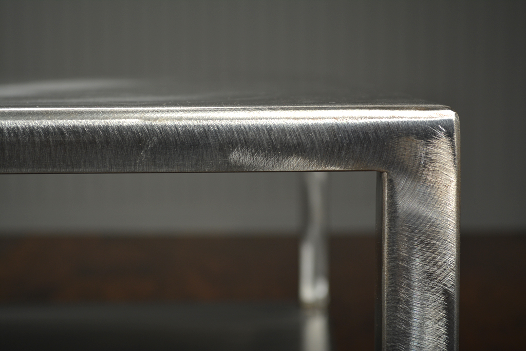 Brushed steel coffee table with two levels, slightly tapered legs, and an open bottom shelf.