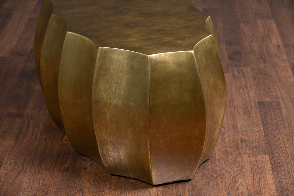 A large, contemporary coffee table with a scalloped edge and an antiqued brass finish.