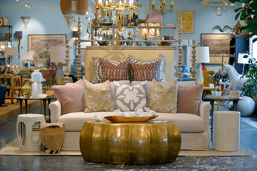 A contemporary scalloped antiqued brass oval coffee table in a store.