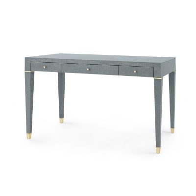 A modern minimalist desk with a gray linen finish and brass accents featuring two drawers and a single shelf presented in a