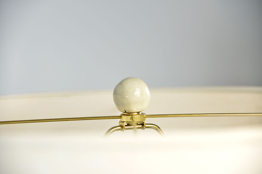 A glazed ceramic egg lamp with a thick wood base and cream linen shade, set against a white background.