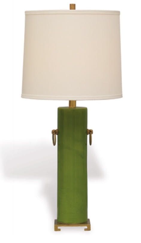 A lamp with a green base and a white shade, standing on a surface.