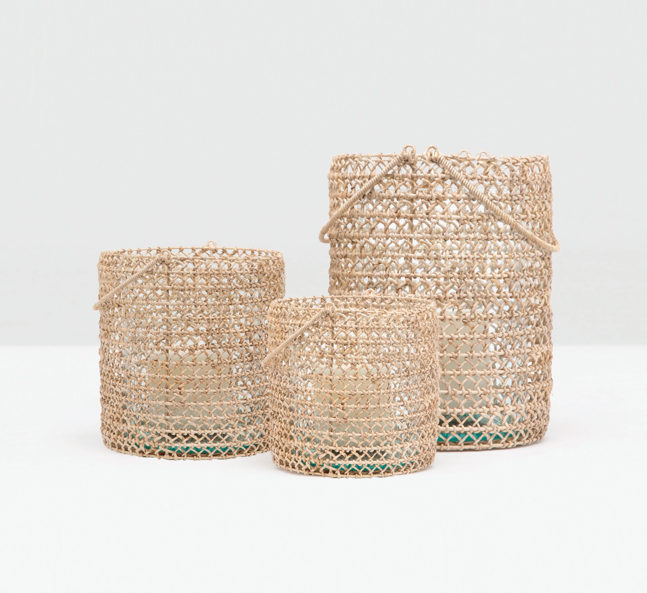Three woven baskets with a natural wicker texture in varying sizes displayed against a white background The largest basket is positioned on