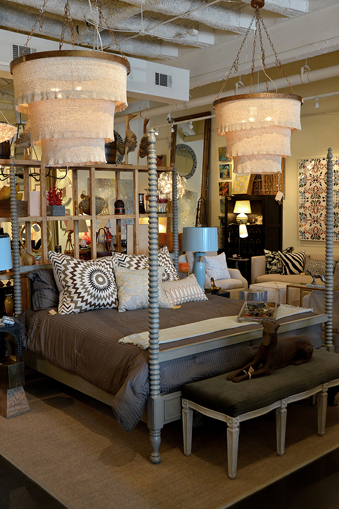 Round three tier beaded chandelier with gold frame and 5 lights, hanging from ceiling in a store.