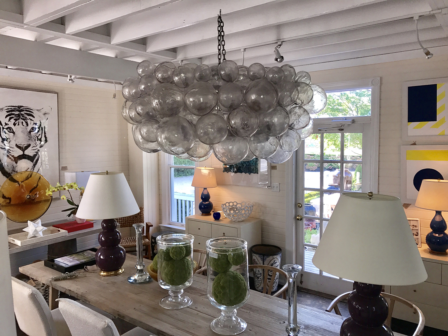Large, modern chandelier with spherical resin bubbles hanging from a central canopy, illuminated by six bulbs, with a chain and ceiling mount.