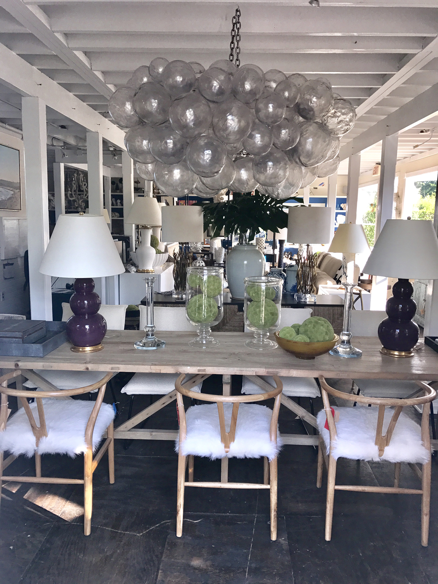 A chandelier with a spherical design, featuring multiple layers and bulbs, hanging from the ceiling in an interior space.