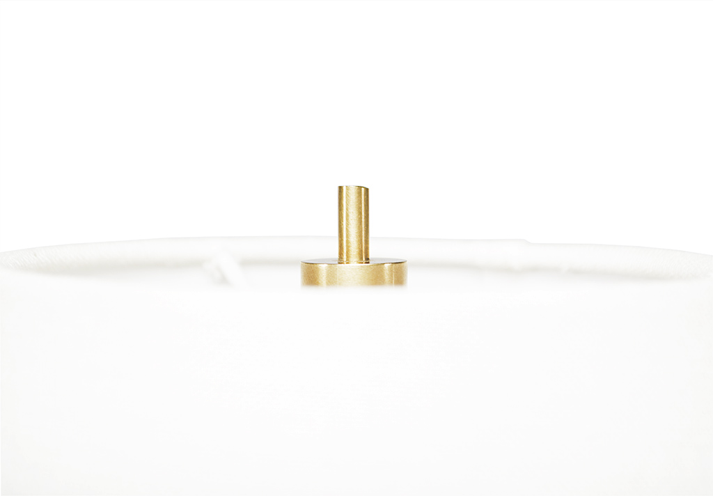 A gold-toned metal table lamp with a clear lampshade and a French wired on-off switch, set against a white background.
