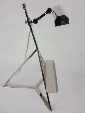 A modern metallic desk lamp with a sleek design featuring a curved neck and adjustable arm standing on a tripod base against