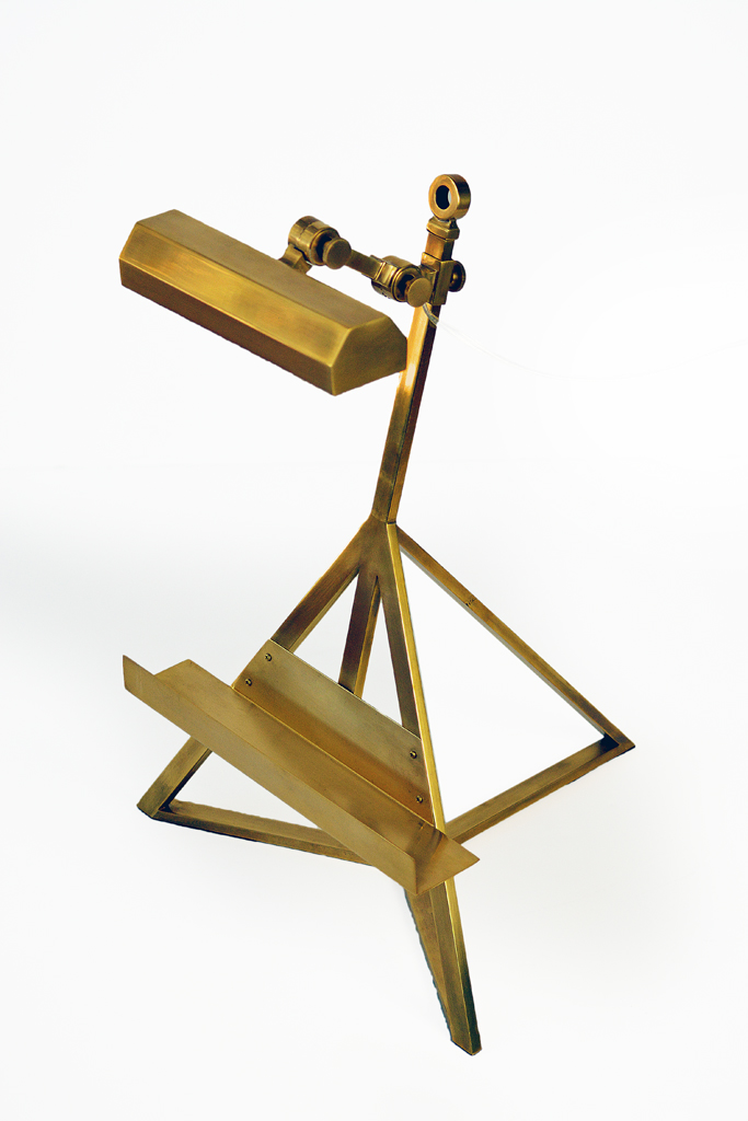 A brass display lamp with a three-tiered stand, placed on a white surface.