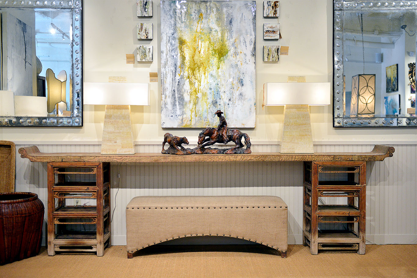 A modern faux bone obelisk table lamp with a rectangular shade, set against a wall with framed artwork and mirrors.
