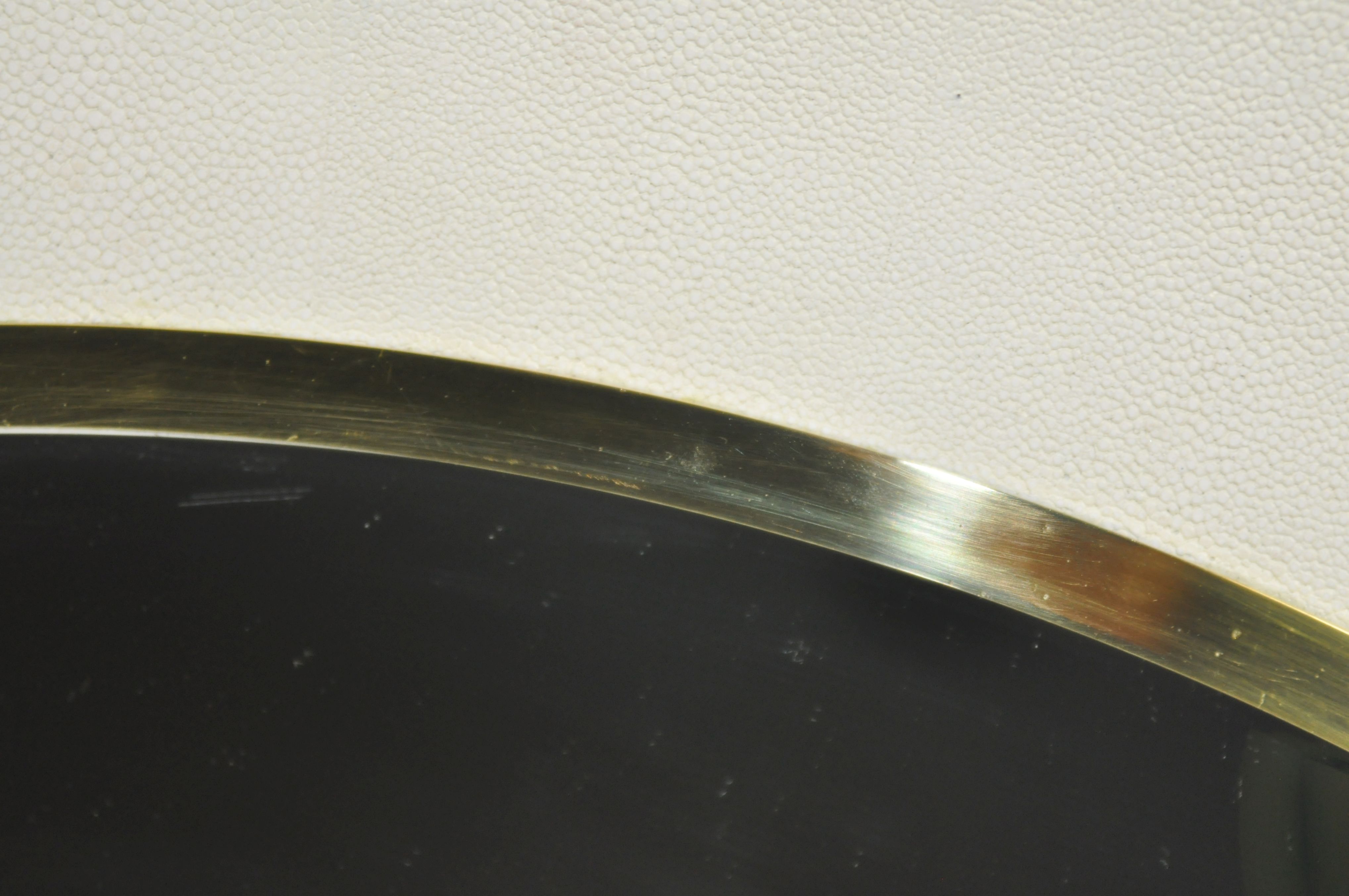 The image is a close-up of a round mirror with a gold frame, showcasing its intricate design and reflective surface.