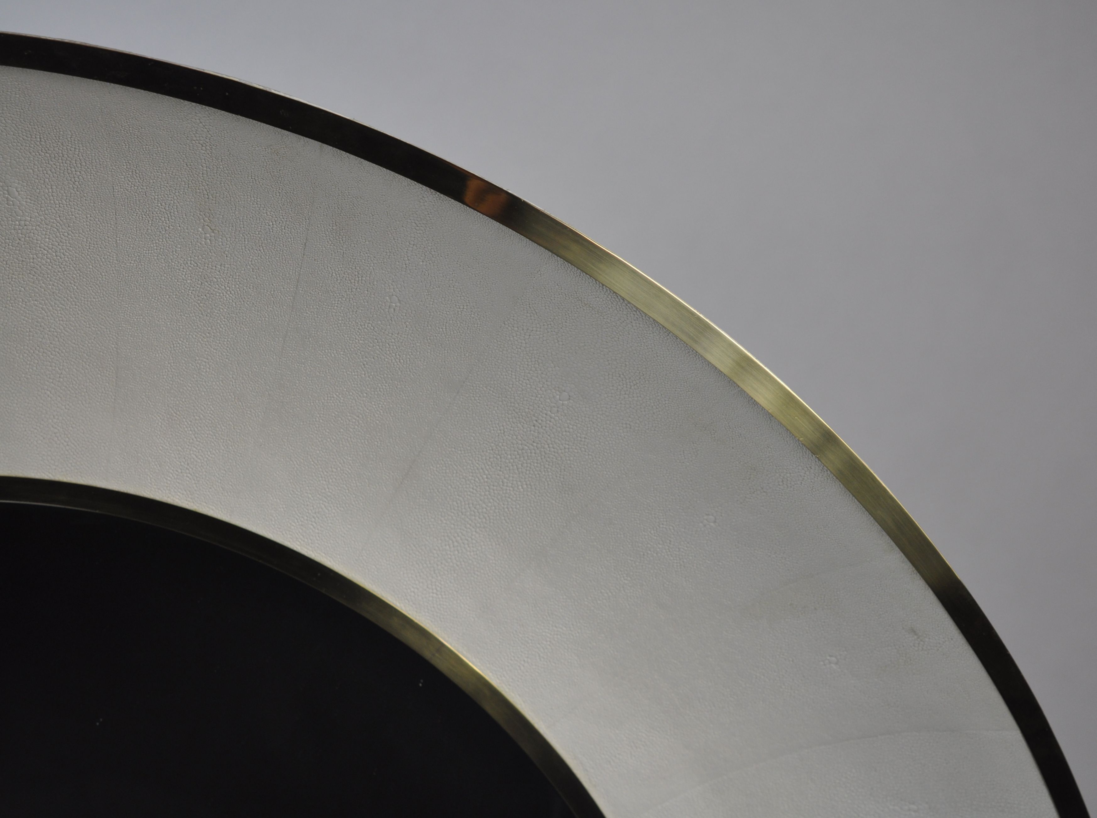 A round mirror with a silver trim and a snow faux shagreen design, presented in a close-up shot.