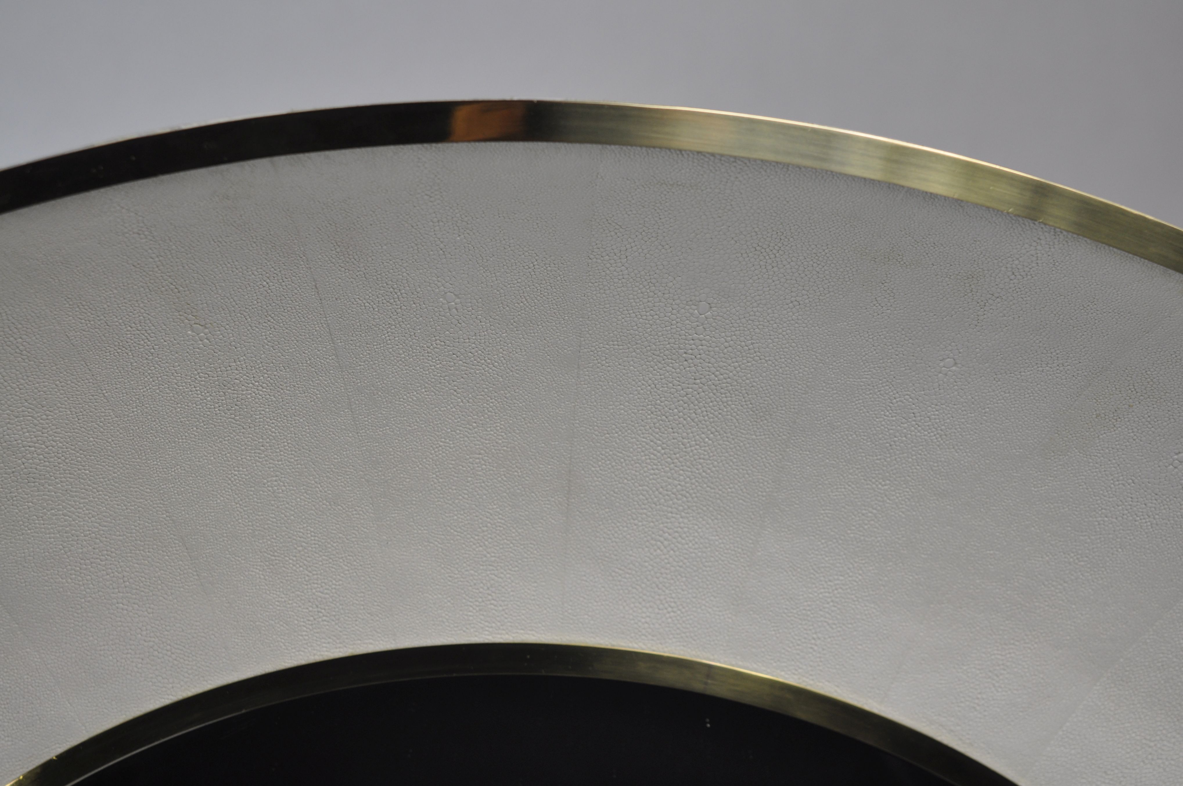 Round mirror with a snow faux shagreen finish and a brass trim, available in other colors as well.