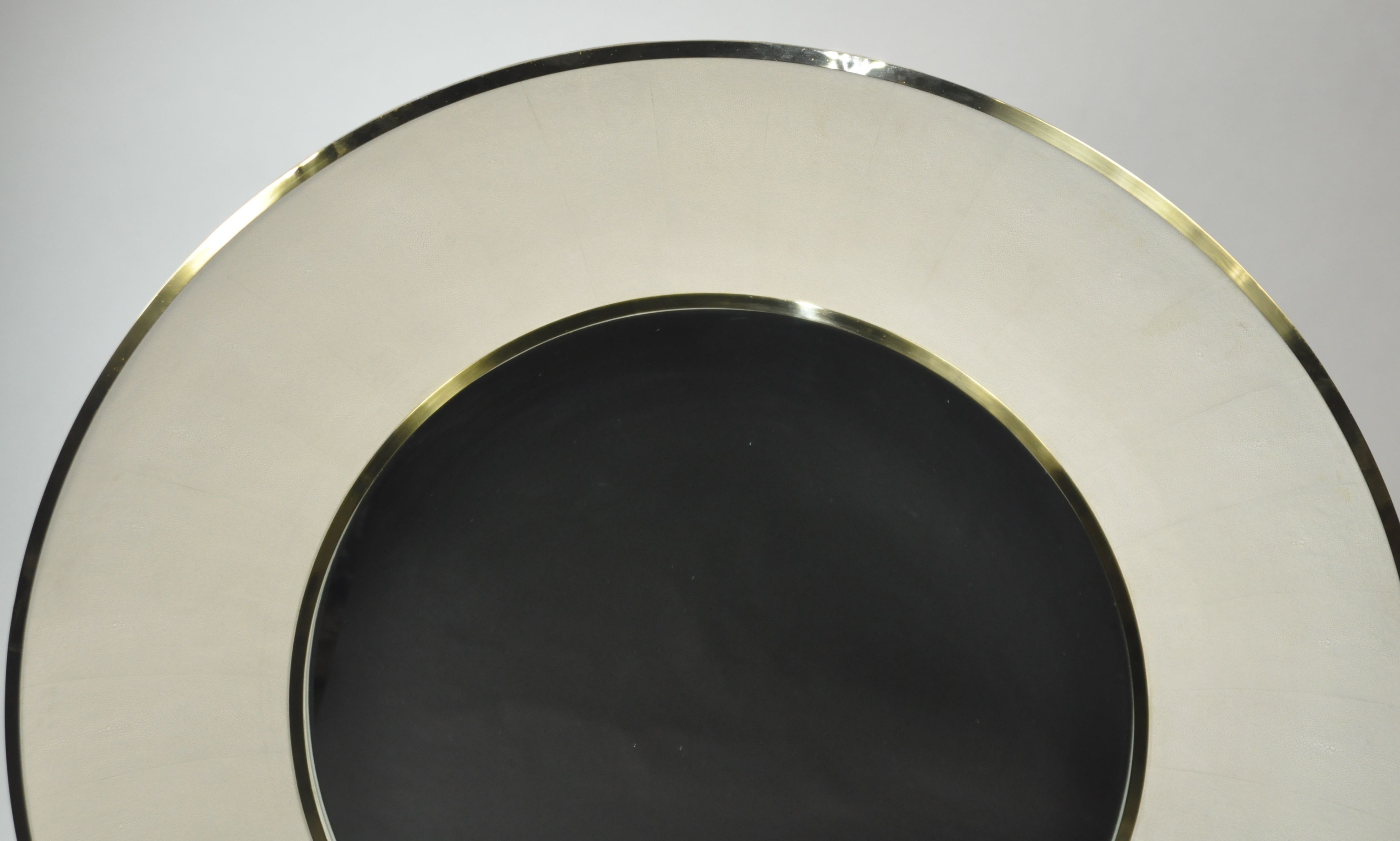 Round mirror with a gold frame and a black center, set against a white background.