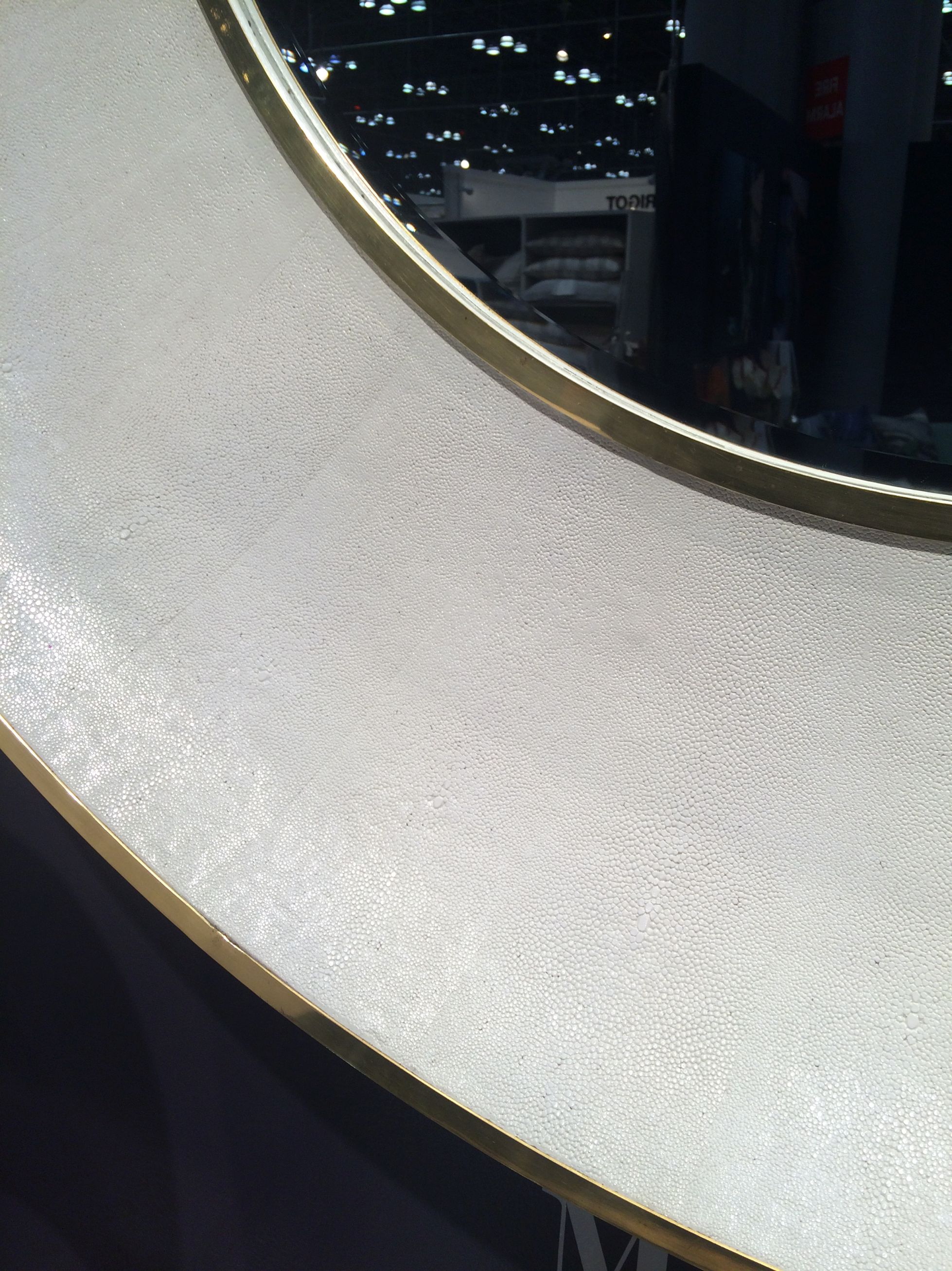 Round mirror with a beveled edge and a silver or brass trim, set against a dark background.