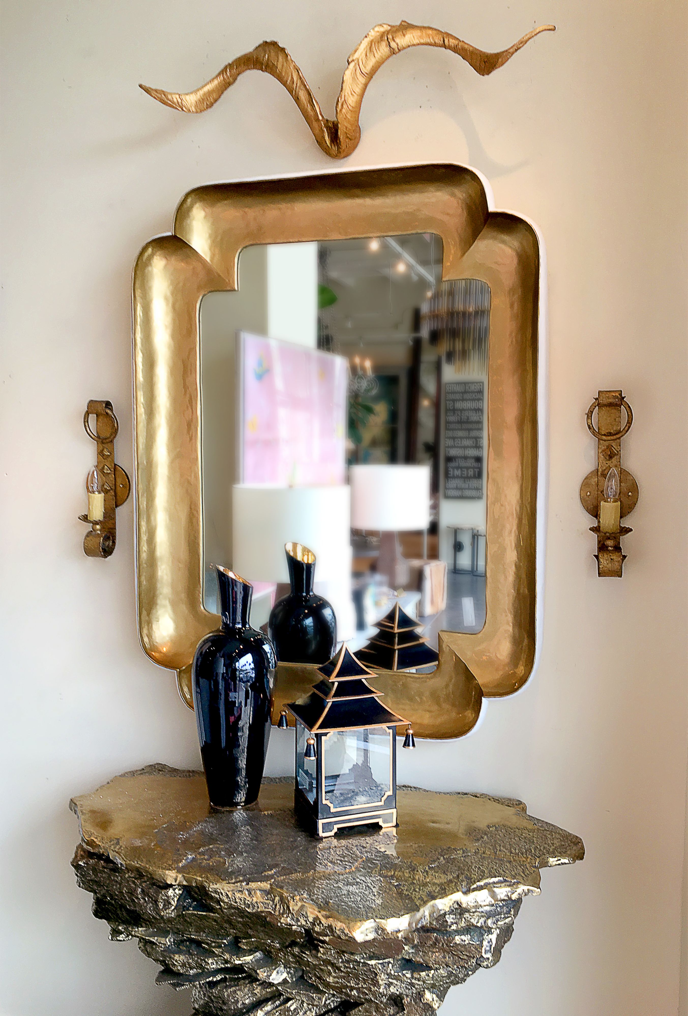 Gold corner wall mirror with a white frame, placed on a table.