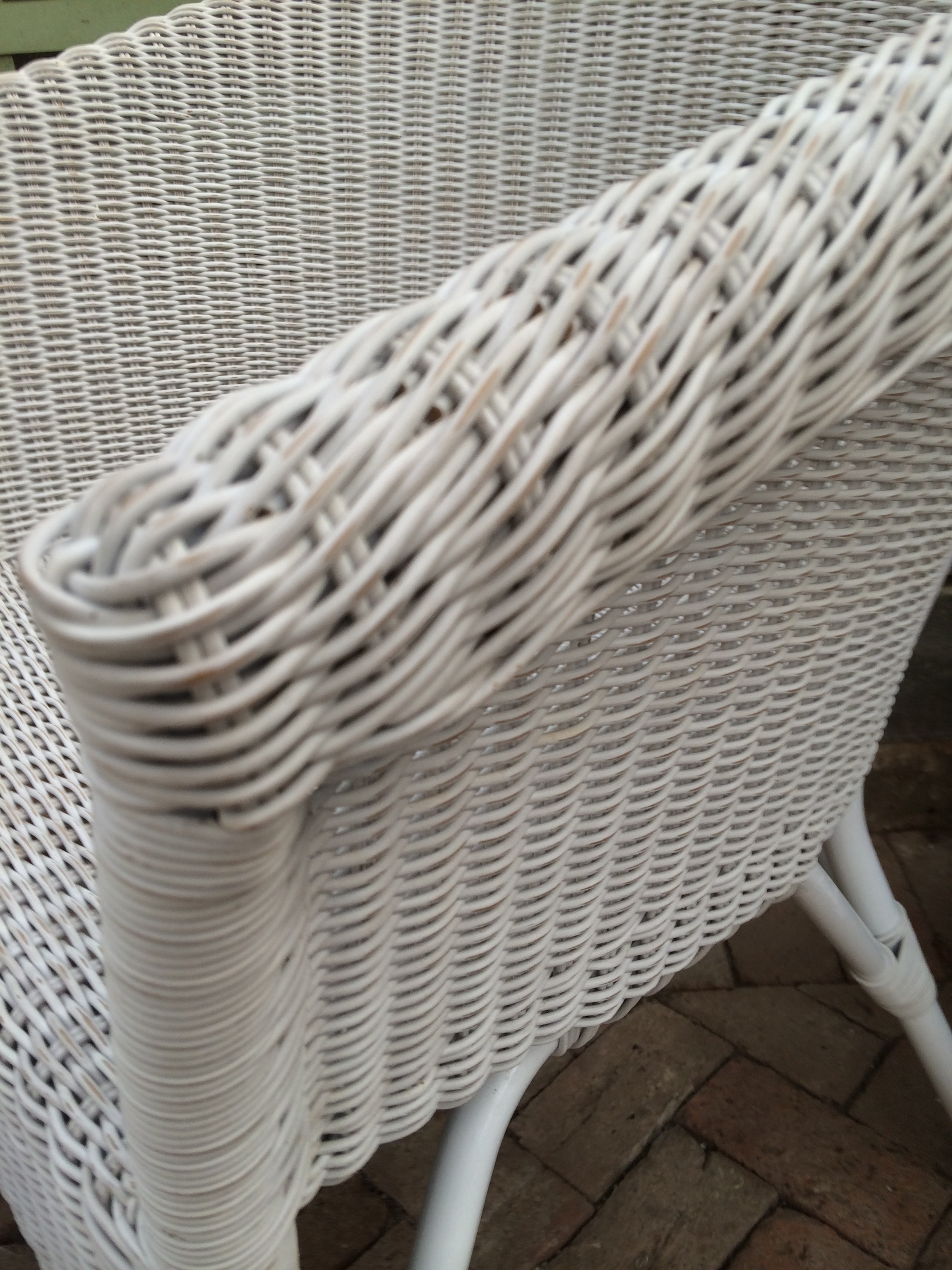 A wicker outdoor armchair with a rounded back, available in white or grey finish.