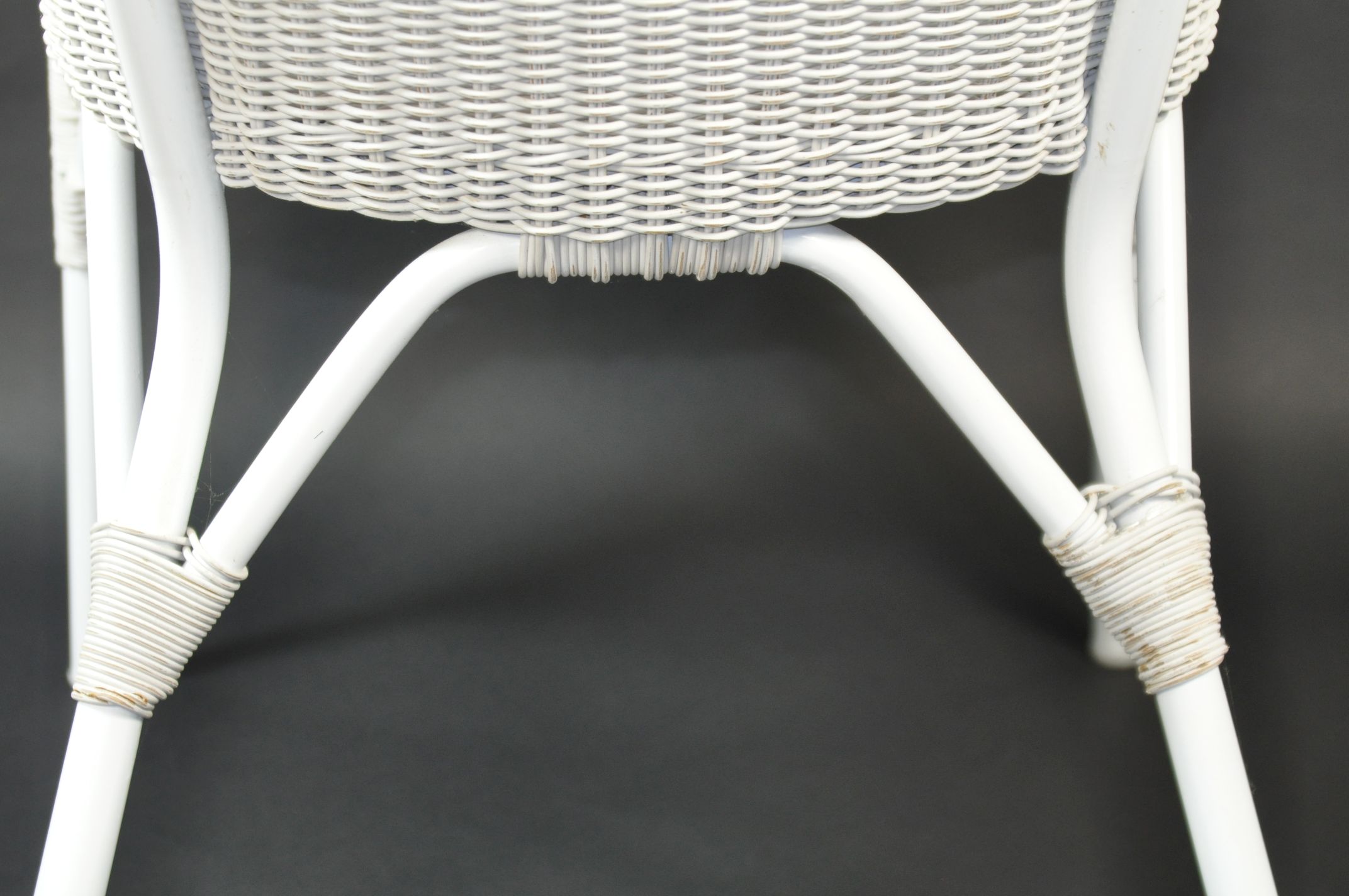 Black and white wicker armchair with a curved backrest, featuring two arms and a cushion seat.
