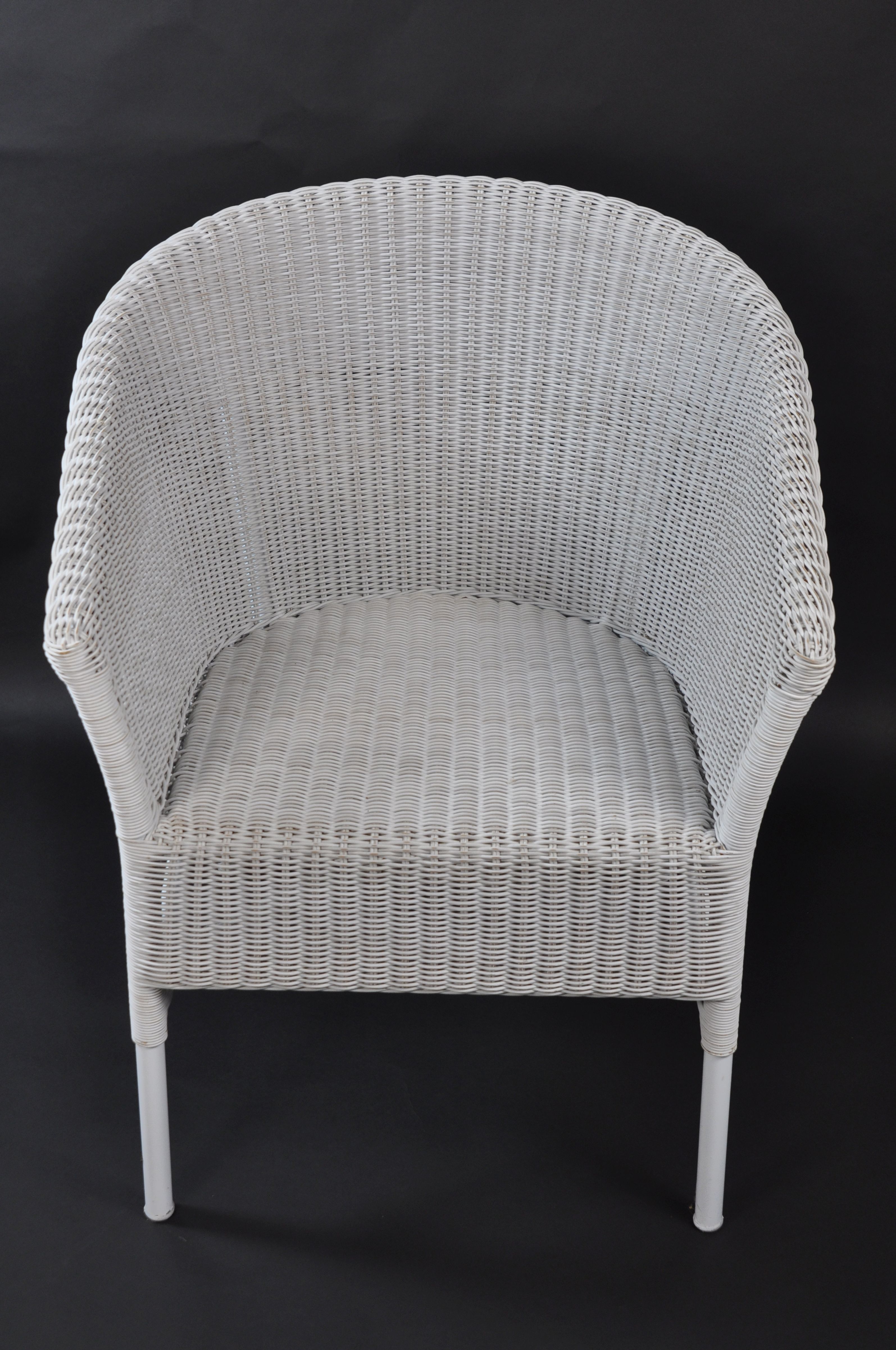 White wicker armchair with a curved backrest, positioned against a black background.