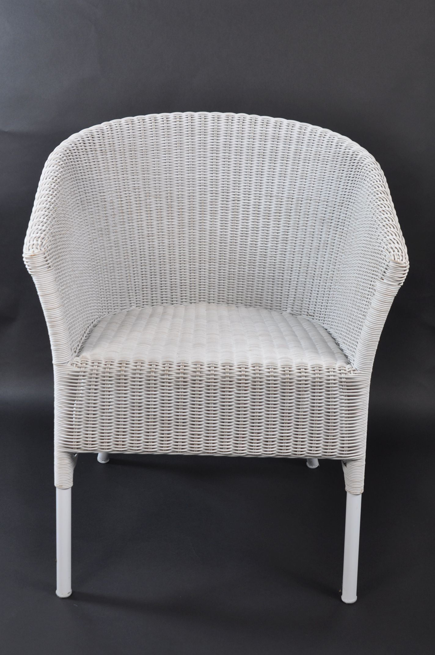 Wicker armchair with a rounded back, set against a dark background.