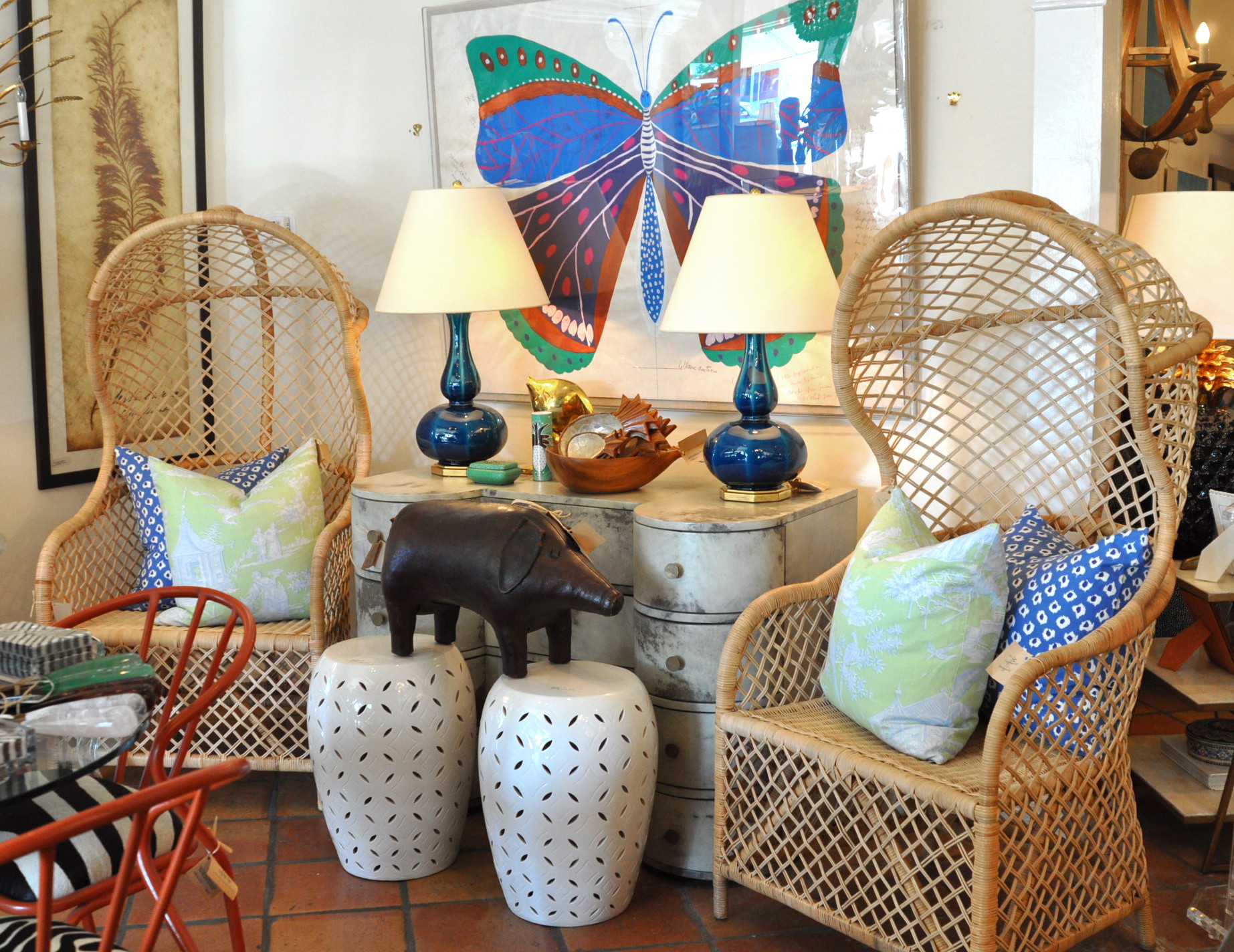 A collection of wicker chairs and stools in a store, with some featuring blue and white accents.