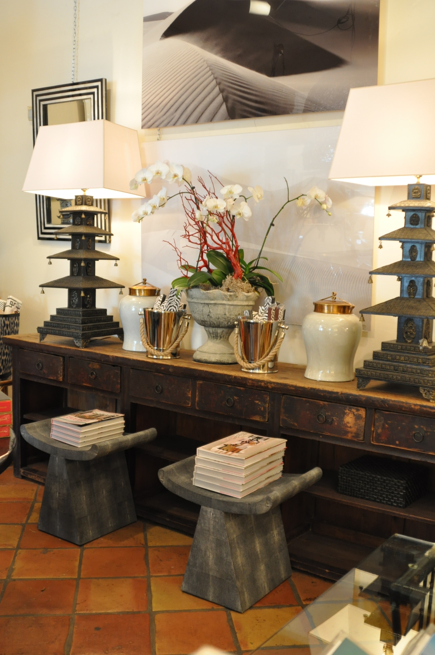 A stool with a cool grey faux shagreen seat, placed in front of a countertop displaying decorative items and books.
