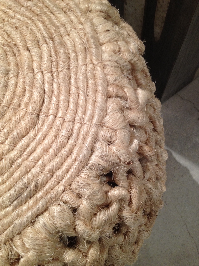 Natural fiber woven into a circular shape, forming a stool with a rope texture and a visible pattern of interwoven strands.