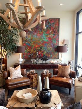 A brown leather sofa in a living room with a painting on the wall and a side table.
