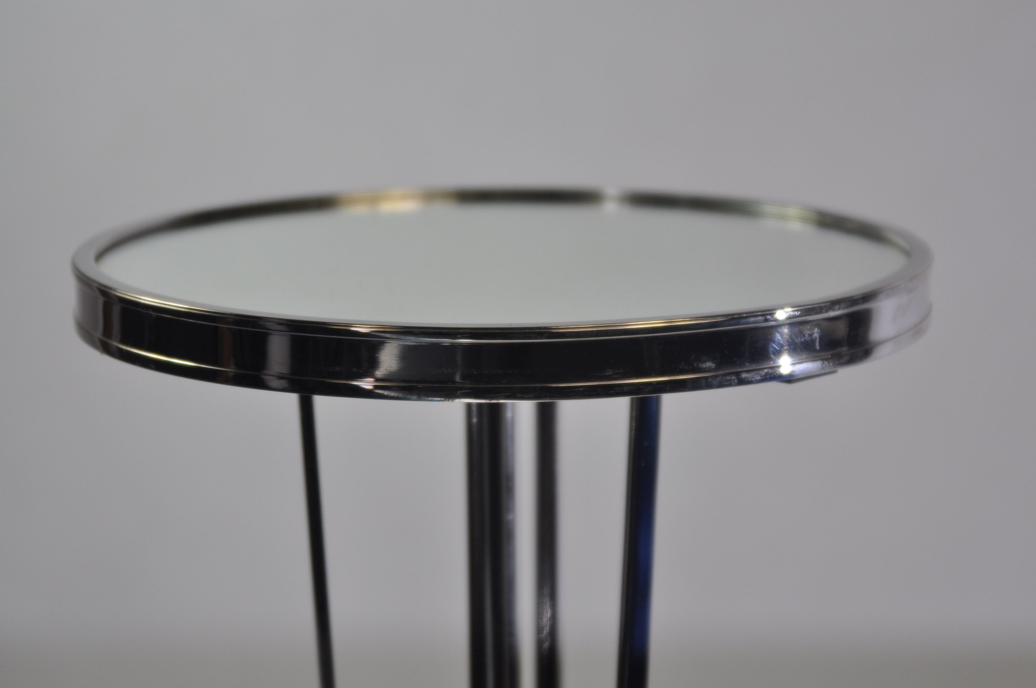 French modern side table with a round mirrored top and a metallic stand.